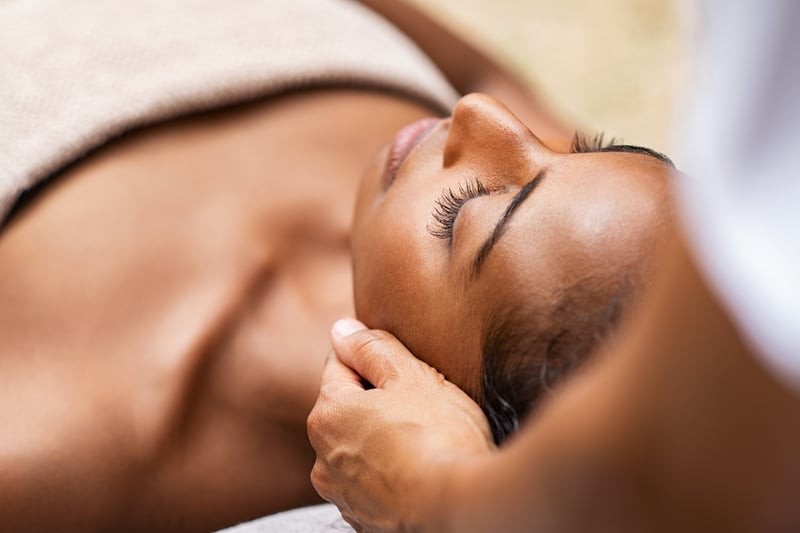 Black woman getting a head massage at a spa