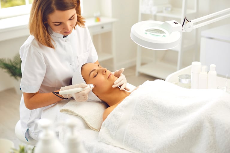 Aesthetician giving a woman microdermabrasion in a spa