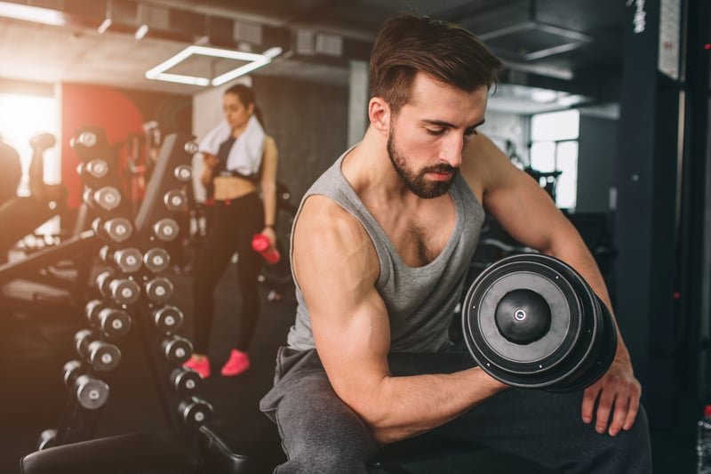 Man doing a curl with dumbell with a woman behind him